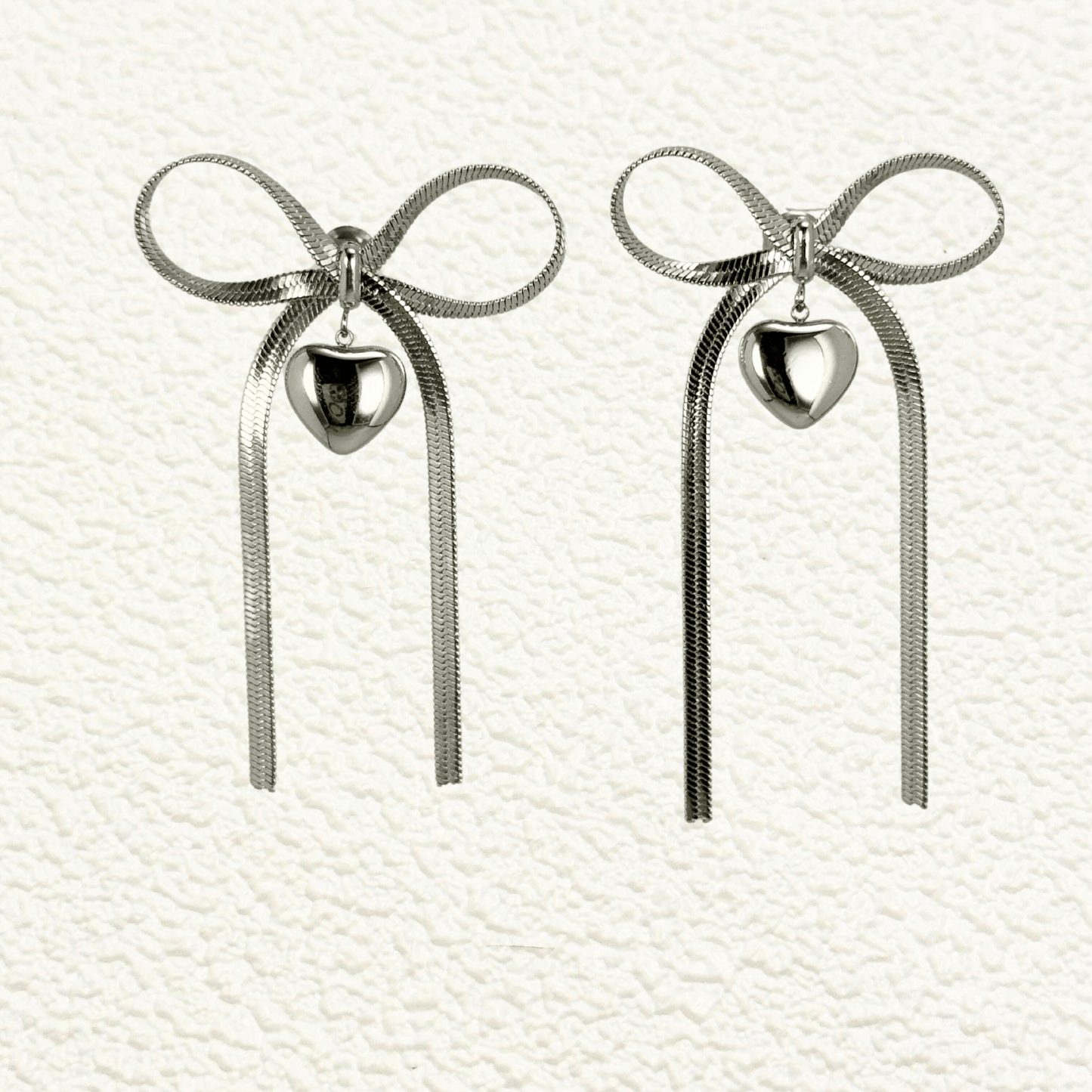 Ribbon bow drop earrings in gold and silver PVD plated stainless steel with long tails and polished heart charms