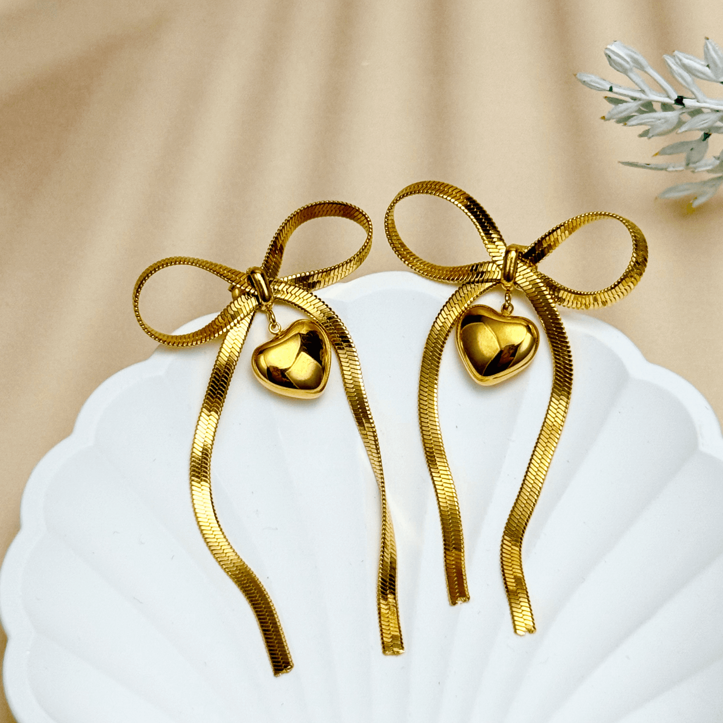 Ribbon bow drop earrings in gold and silver PVD plated stainless steel with long tails and polished heart charms