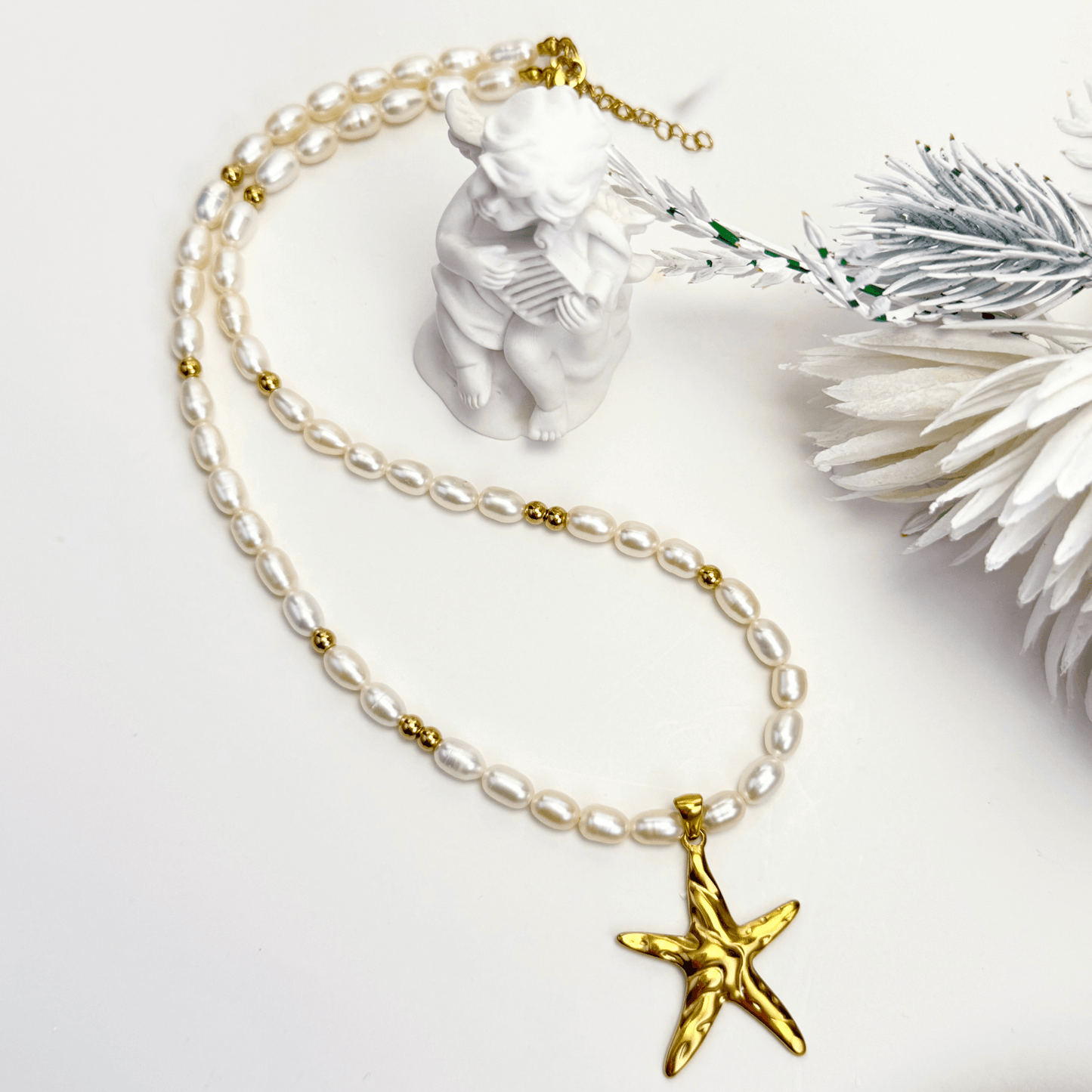 Pearl necklace with a gold starfish pendant on a white background