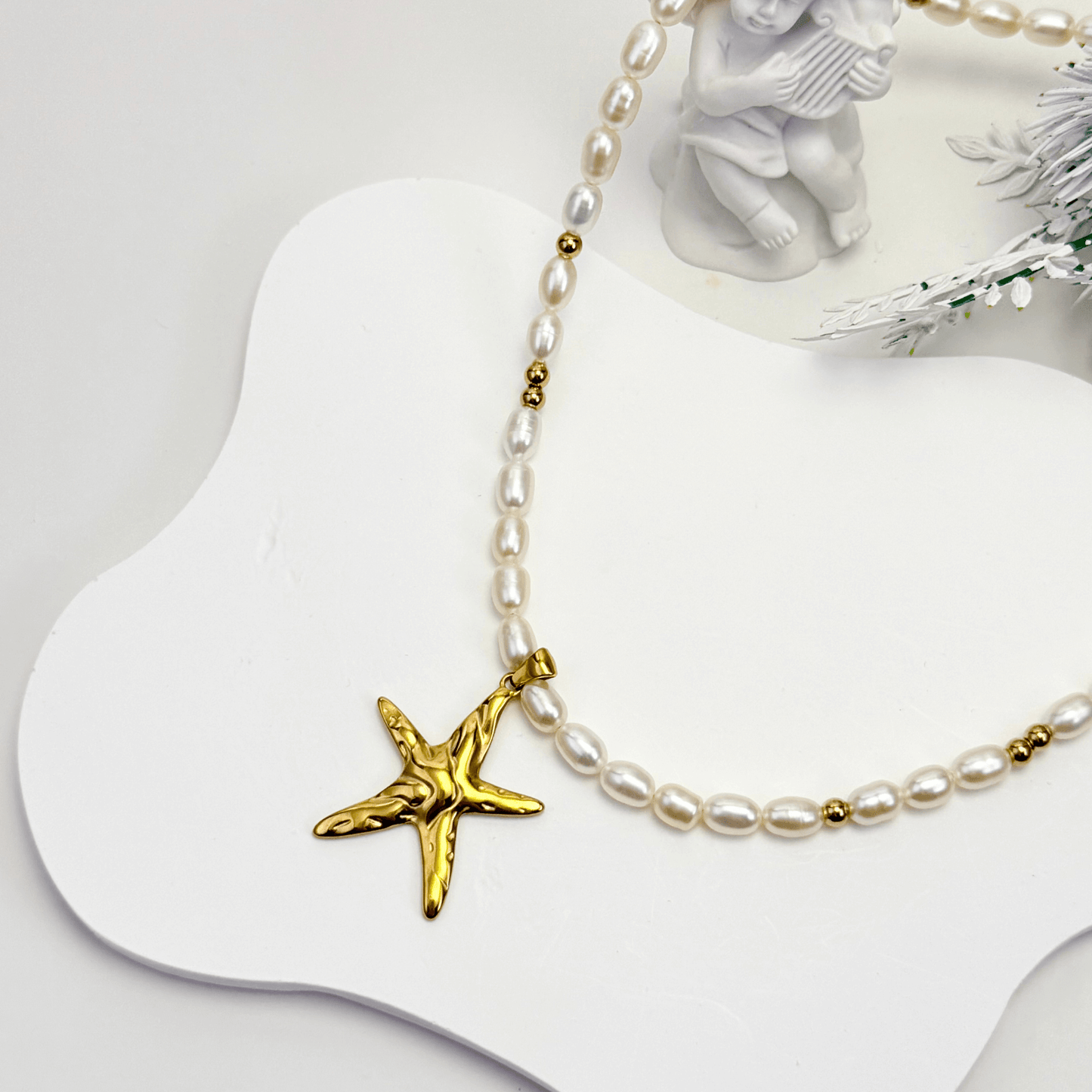 Pearl necklace with a gold starfish pendant on a white surface