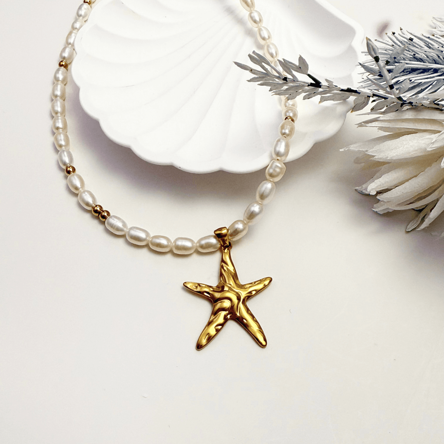 Pearl necklace with a gold starfish pendant on a white background