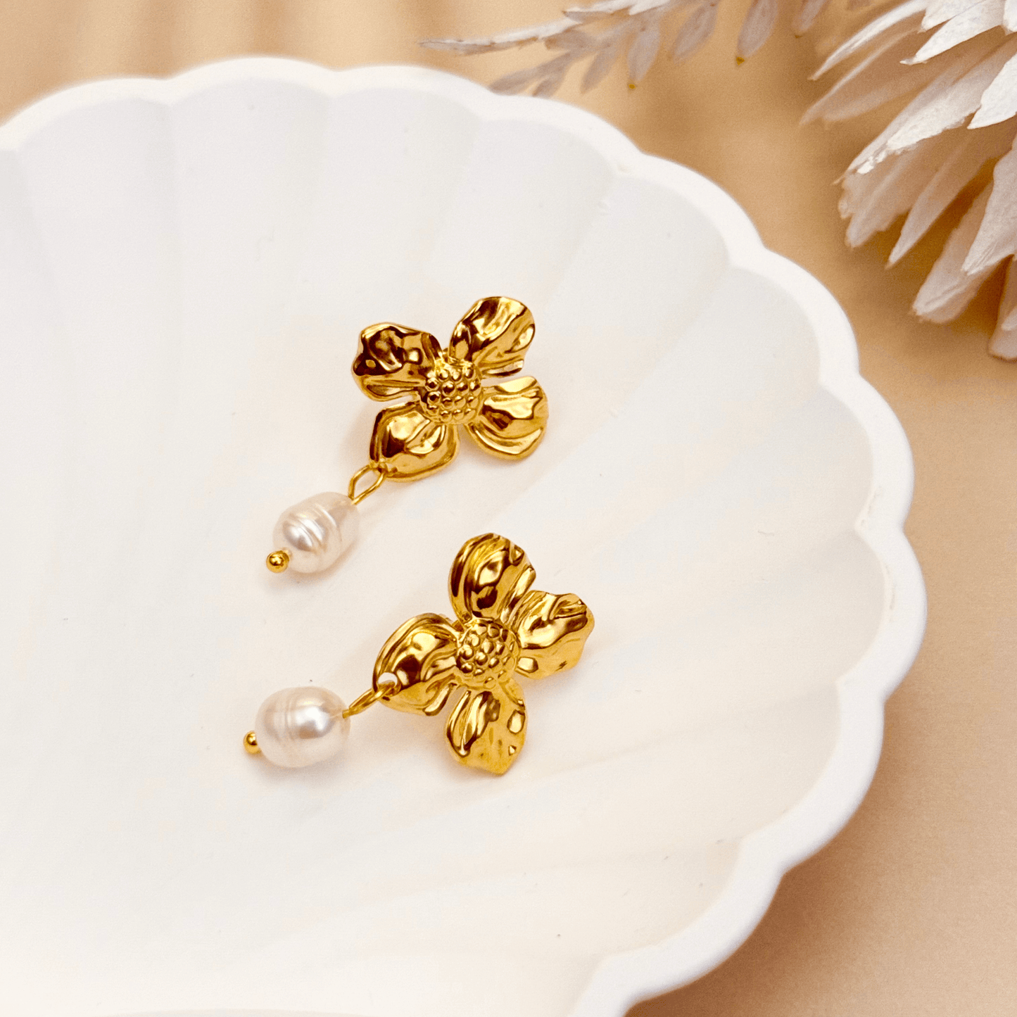 Textured gold floral pearl drop earrings with white teardrop-shaped pearls on waterproof stainless steel studs