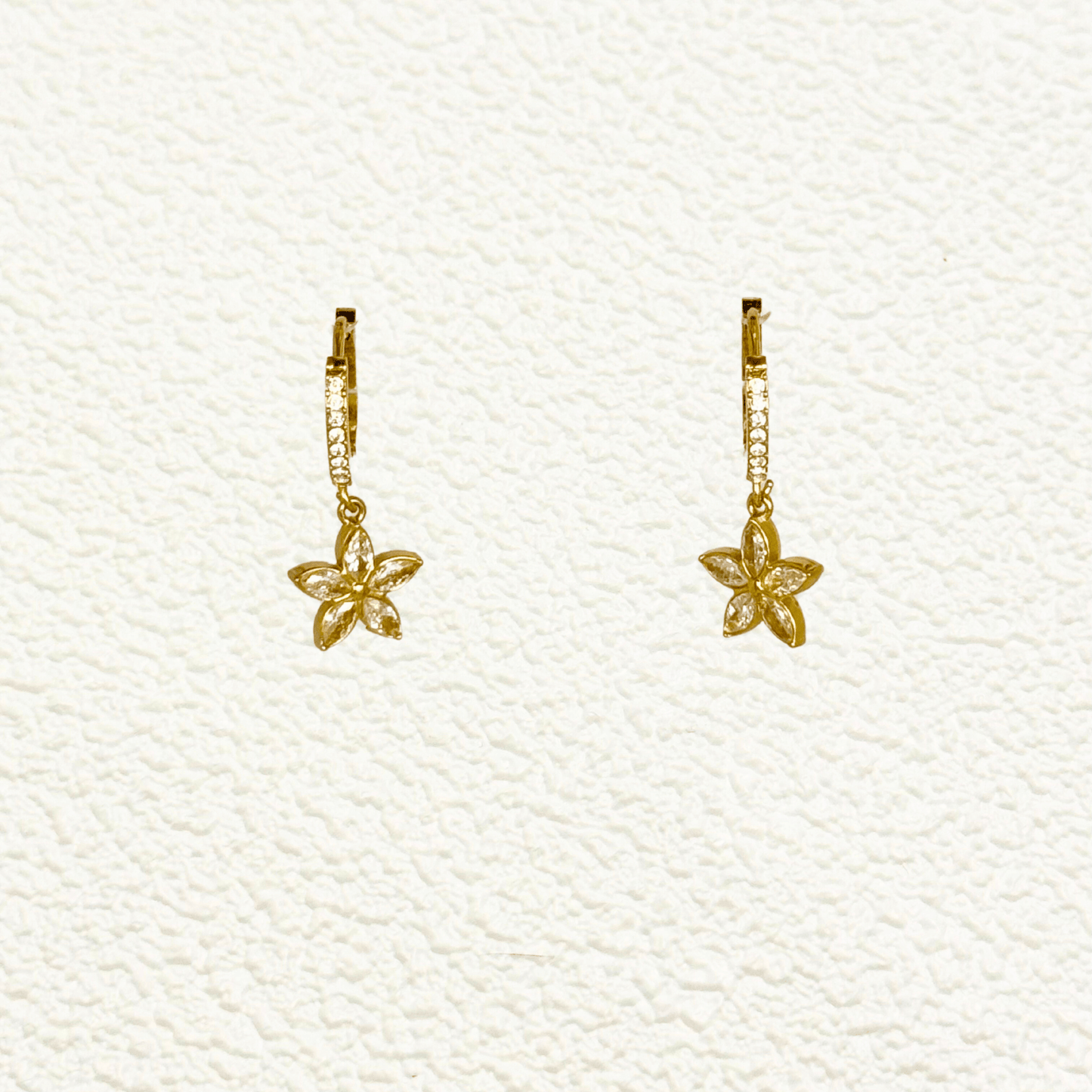 tiny gold huggie earrings featuring a five-petal flower-shaped cubic zirconia charm drop, set in polished gold-plated stainless steel with additional zircons on the hoop, lightweight and waterproof