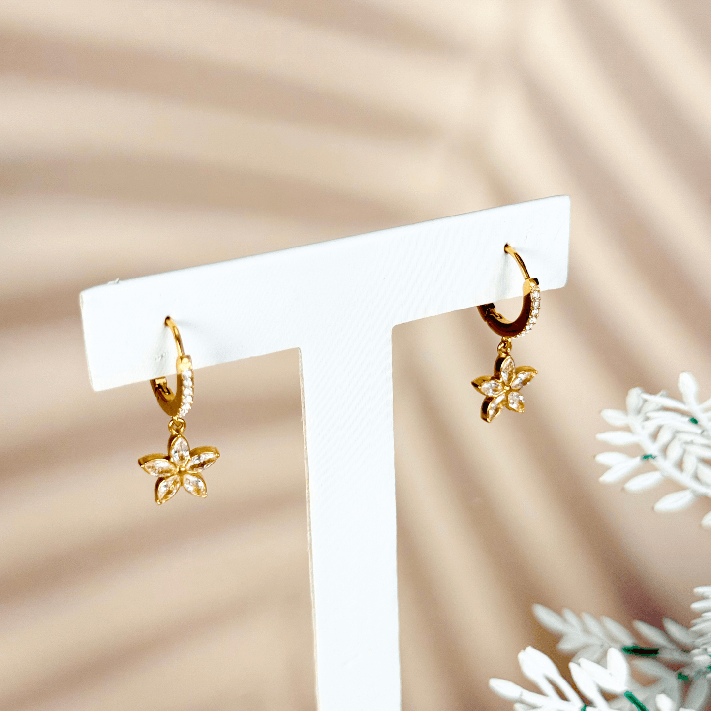 tiny gold huggie earrings featuring a five-petal flower-shaped cubic zirconia charm drop, set in polished gold-plated stainless steel with additional zircons on the hoop, lightweight and waterproof