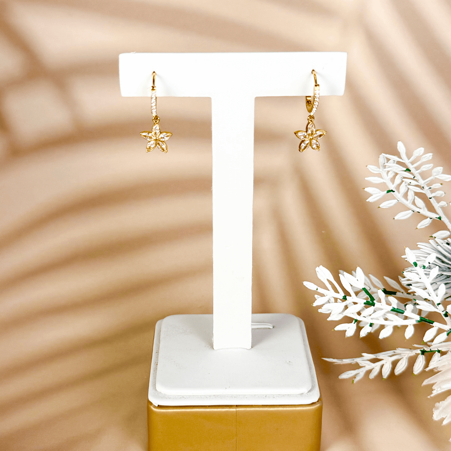 tiny gold huggie earrings featuring a five-petal flower-shaped cubic zirconia charm drop, set in polished gold-plated stainless steel with additional zircons on the hoop, lightweight and waterproof