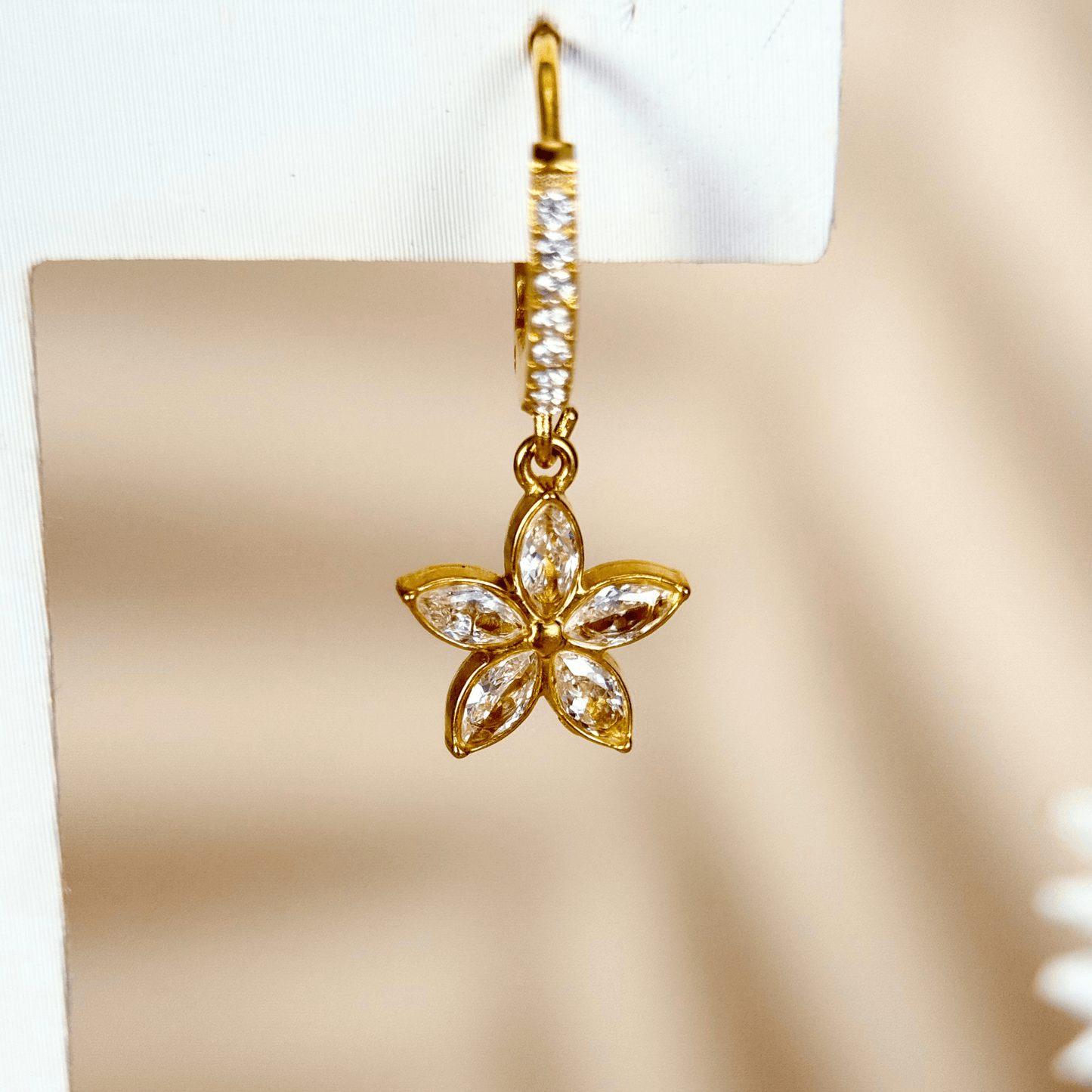 tiny gold huggie earrings featuring a five-petal flower-shaped cubic zirconia charm drop, set in polished gold-plated stainless steel with additional zircons on the hoop, lightweight and waterproof