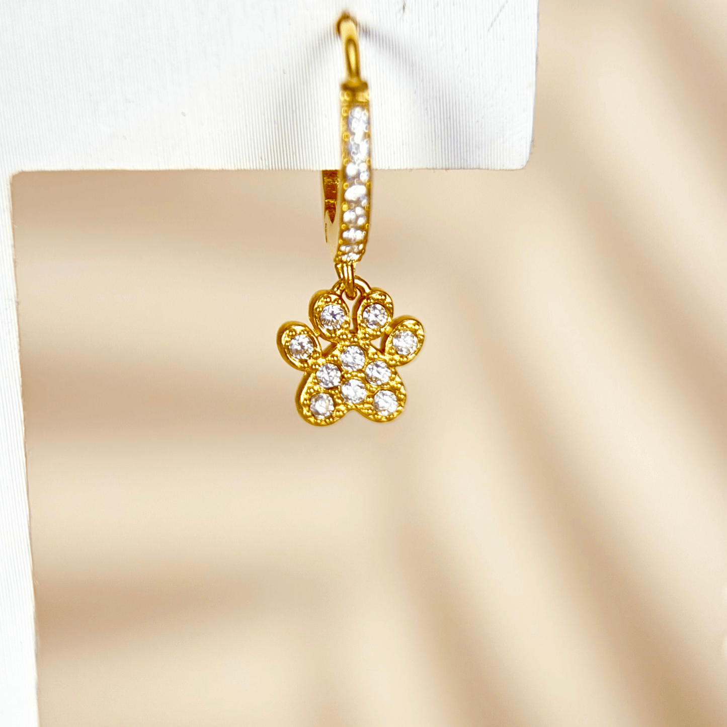 Tiny gold huggie earrings with a sparkling zircon-studded paw charm, waterproof hypoallergenic jewellery for animal lovers or pet parents