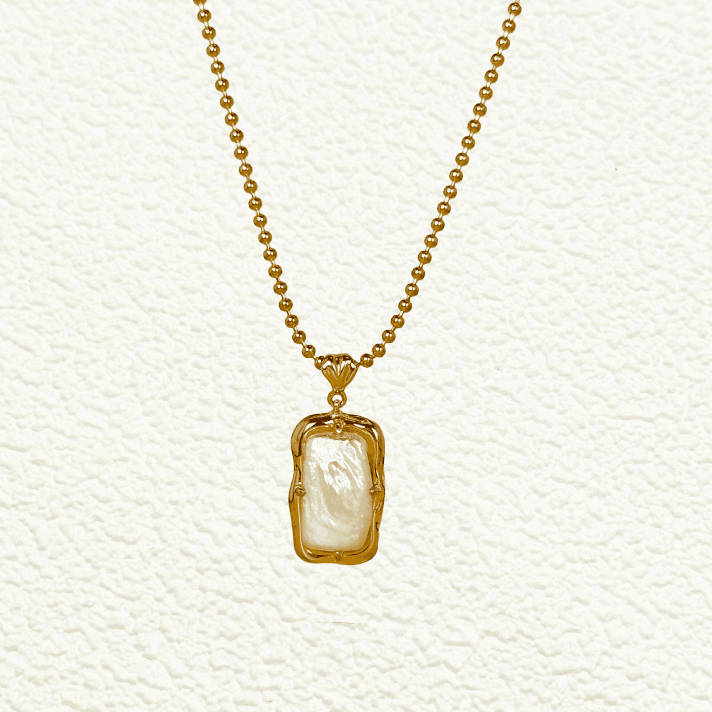 vintage baroque pearl pendant necklace with rectangular pearl and gold-plated silver beaded chain displayed on a jewellery bust