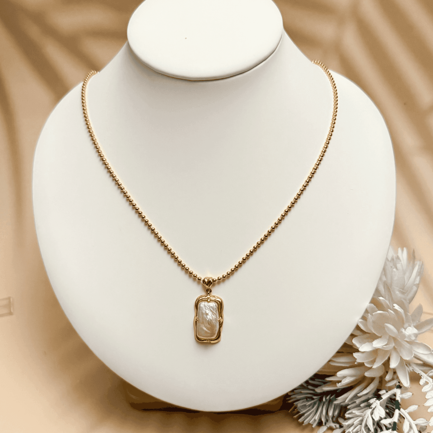 vintage baroque pearl pendant necklace with rectangular pearl and gold-plated silver beaded chain displayed on a jewellery bust