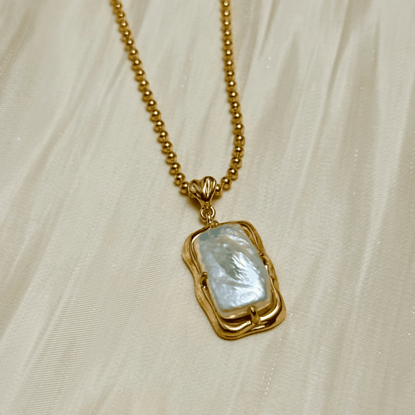 vintage baroque pearl pendant necklace with rectangular pearl and gold-plated silver beaded chain displayed on a jewellery bust
