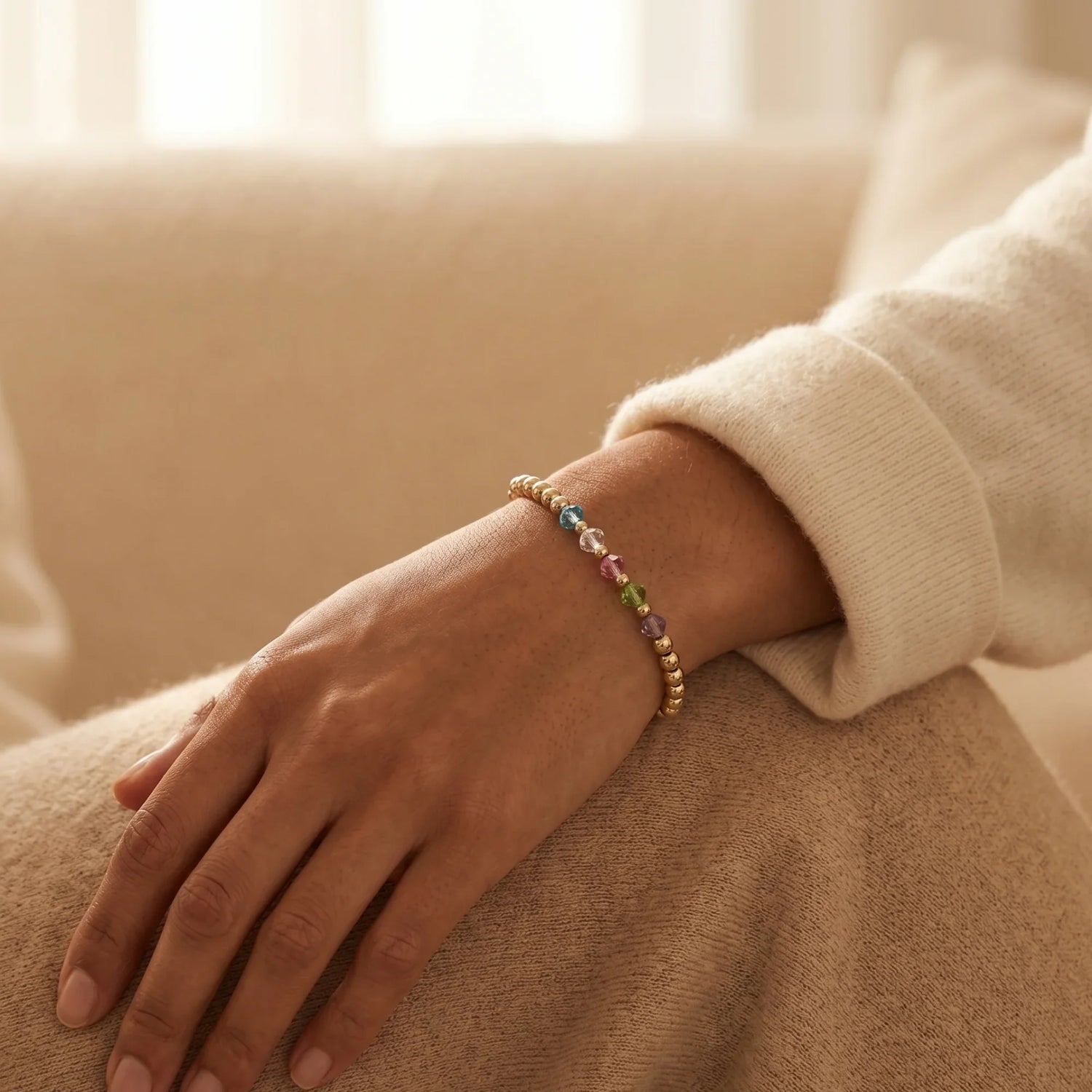 A close-up of a hand wearing a stacked gold bracelet collection, featuring a mix of polished bangle, beaded bracelet, dainty chain, and zircon-accented designs—perfect for stylish layering and everyday elegance.