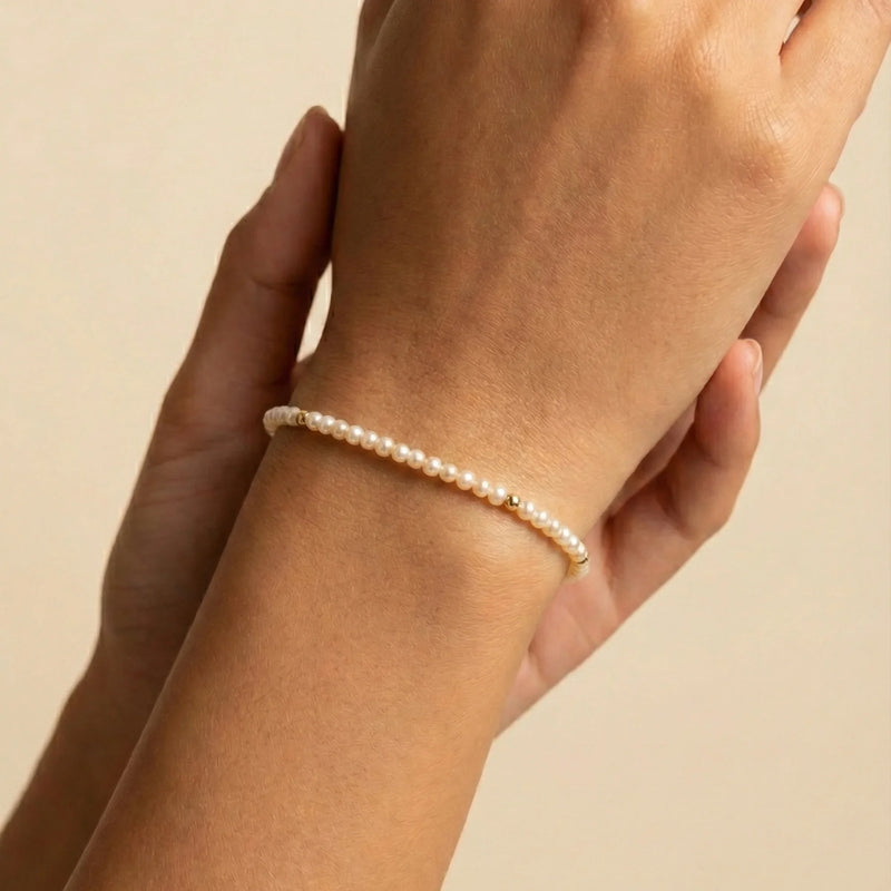 A close-up of a hand wearing a stacked gold bracelet collection, featuring a mix of polished bangle, beaded bracelet, dainty chain, and zircon-accented designs—perfect for stylish layering and everyday elegance.