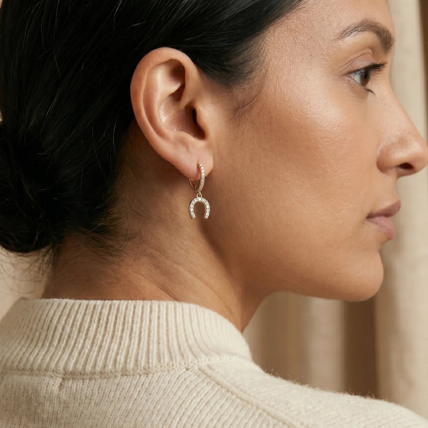 Woman wearing statement gold earrings with a ribbon and heart charm design, perfect for showcasing MXW Jewellery’s elegant earring collection.