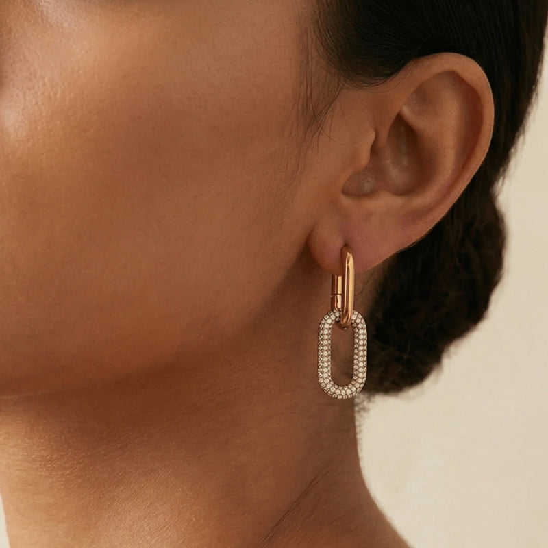 Woman wearing statement gold earrings with a ribbon and heart charm design, perfect for showcasing MXW Jewellery’s elegant earring collection.