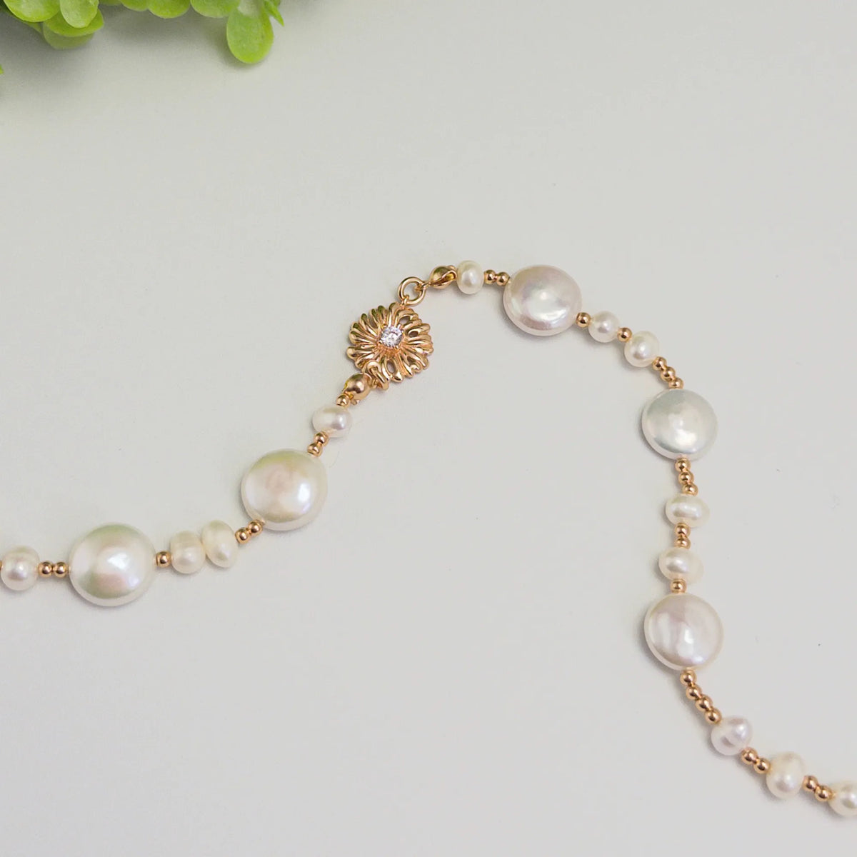 Gold vermeil necklace of coin and round freshwater pearls with small gold beads and a sculpted daisy connector