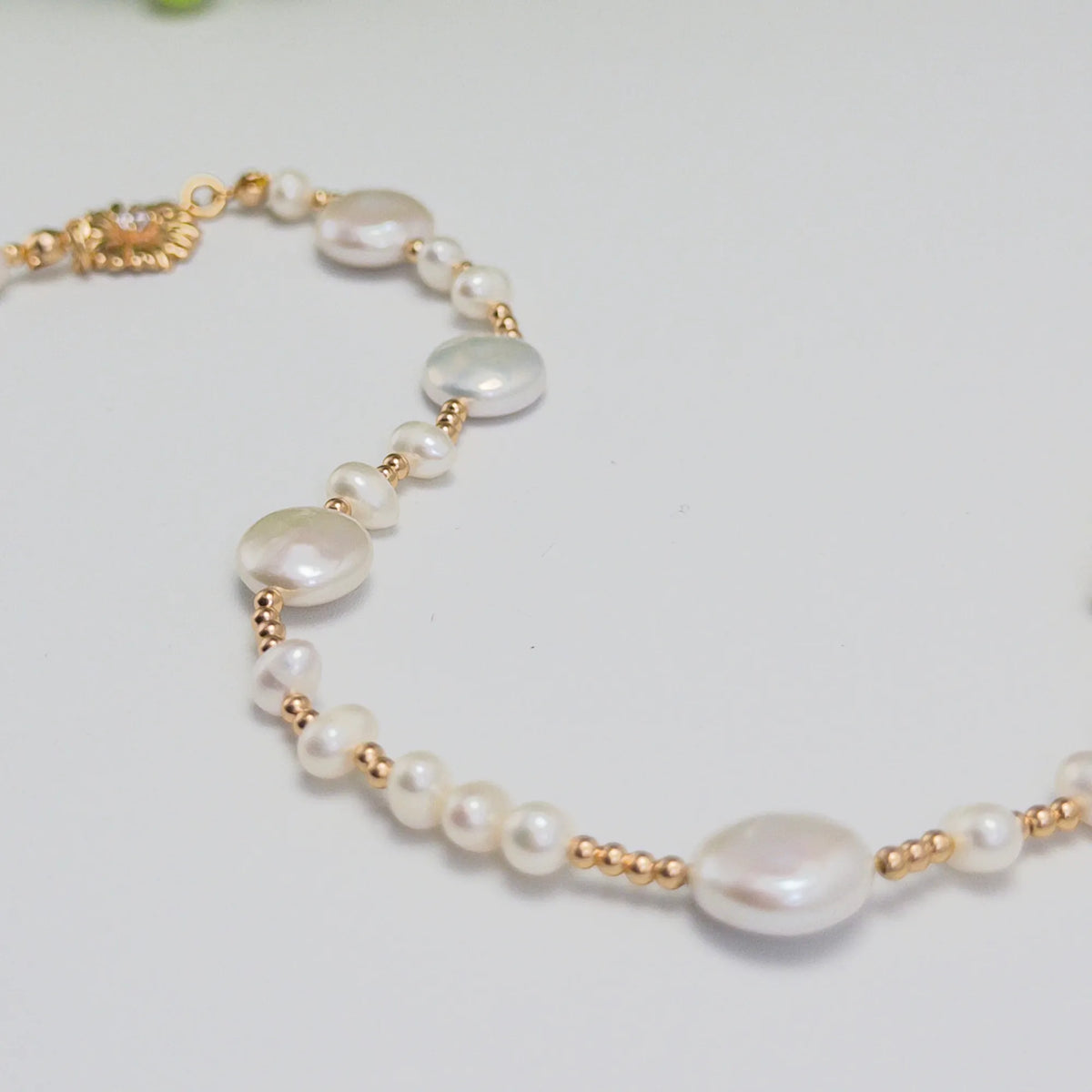 Gold vermeil necklace of coin and round freshwater pearls with small gold beads and a sculpted daisy connector