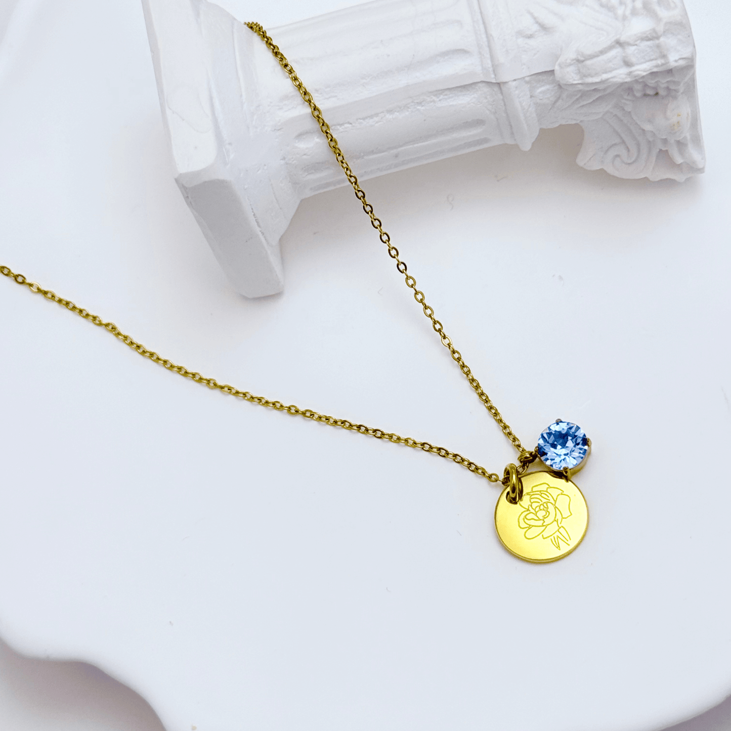 gold birth month necklace with blue crystal and engraved flower pendant