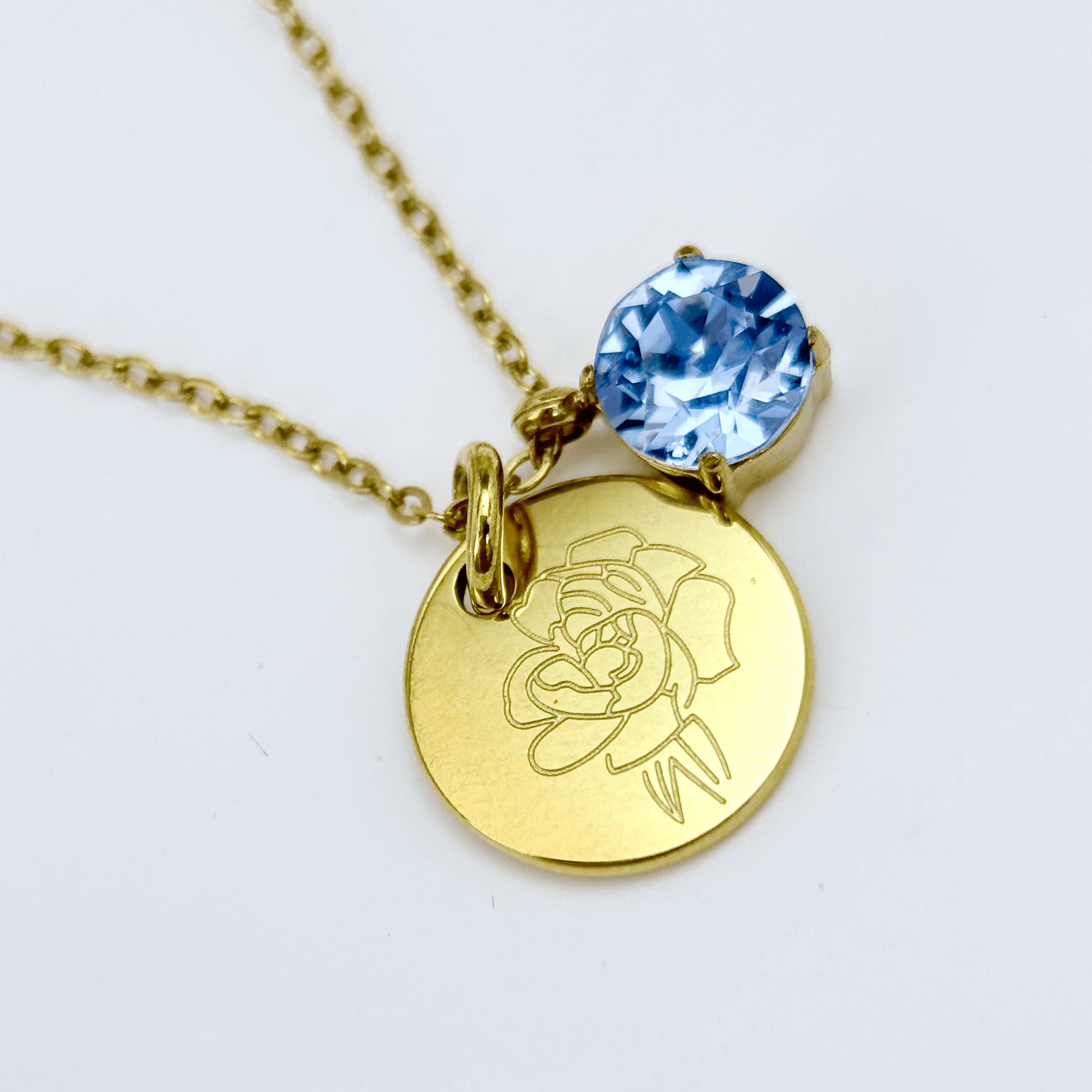 gold birth month necklace with blue crystal and engraved flower pendant