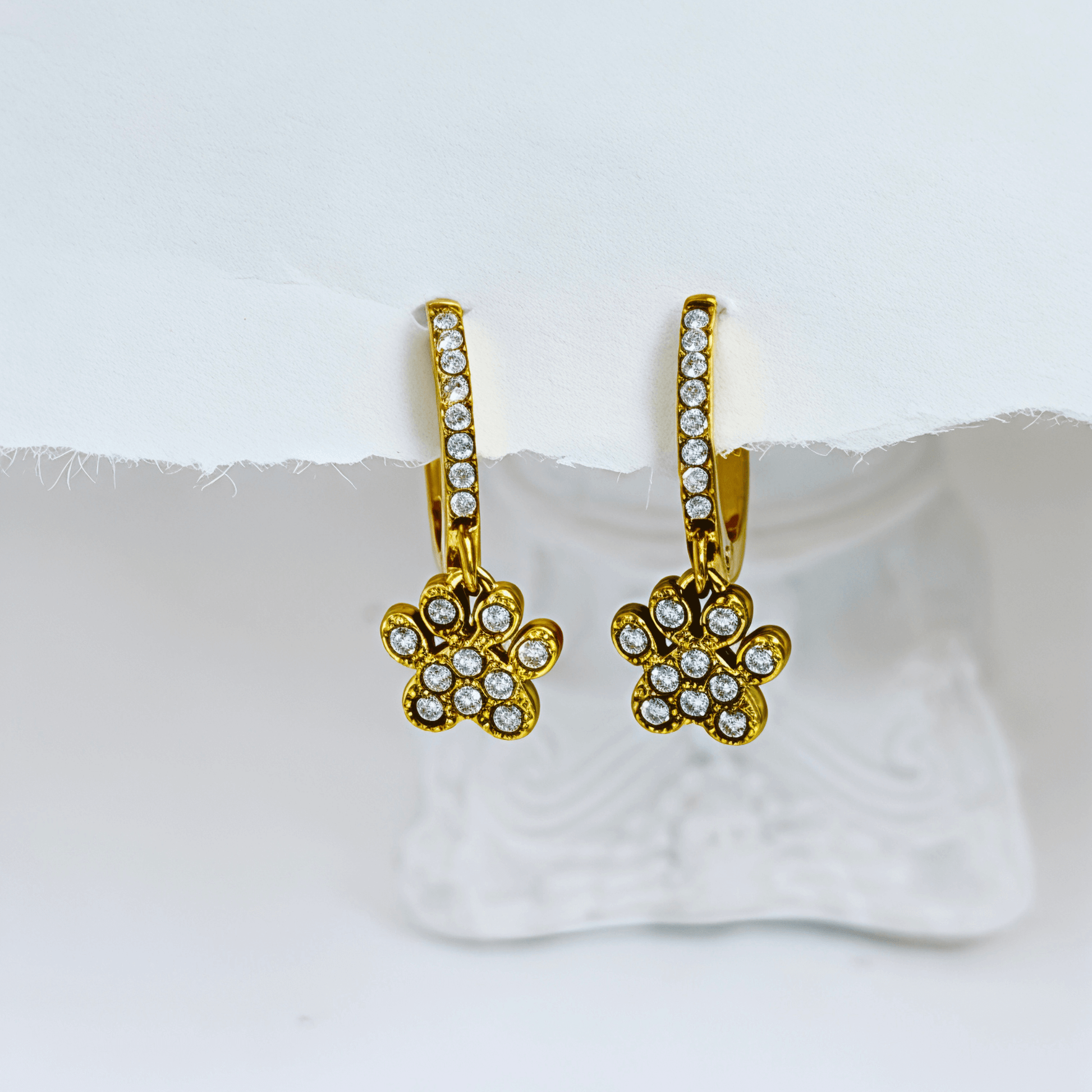 Close up of Gold Paw Print Huggie Earrings featuring paved crystals and a high-polish finish by MXW Jewellery