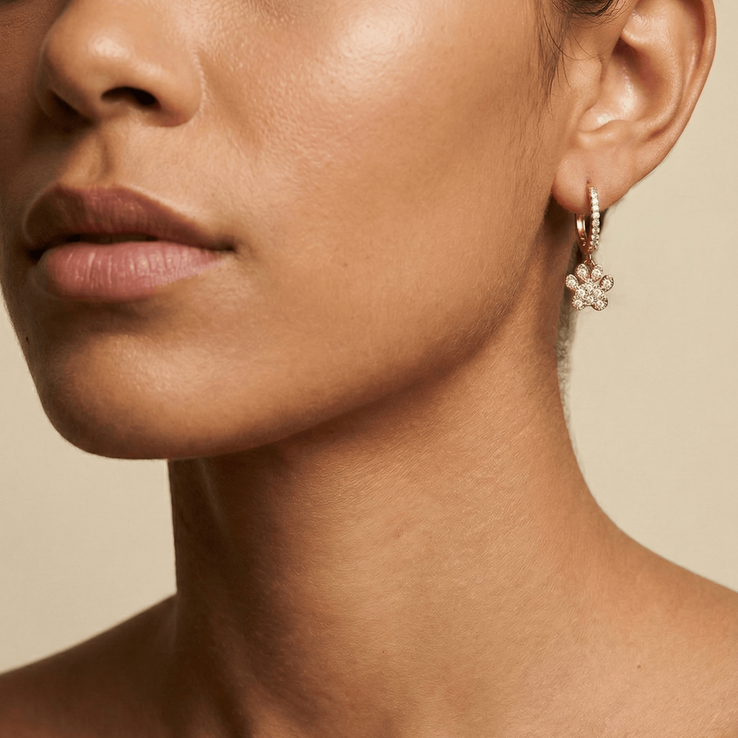 Close up of Gold Paw Print Huggie Earrings featuring paved crystals and a high-polish finish by MXW Jewellery