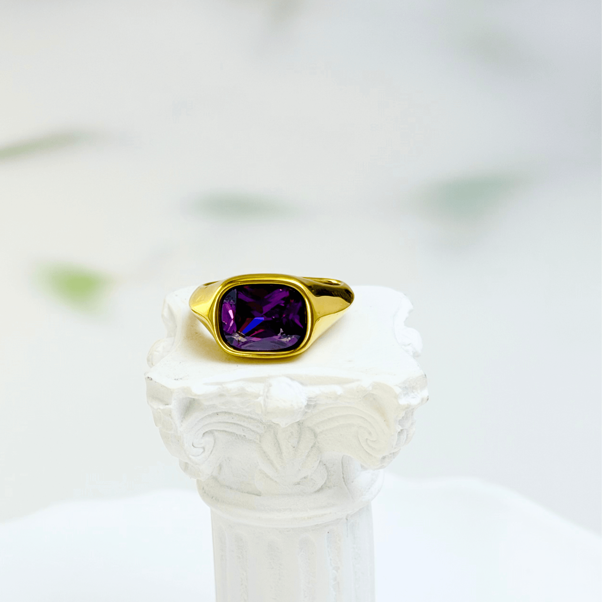 Gold ring with a cushion-cut amethyst-purple zircon gemstone.