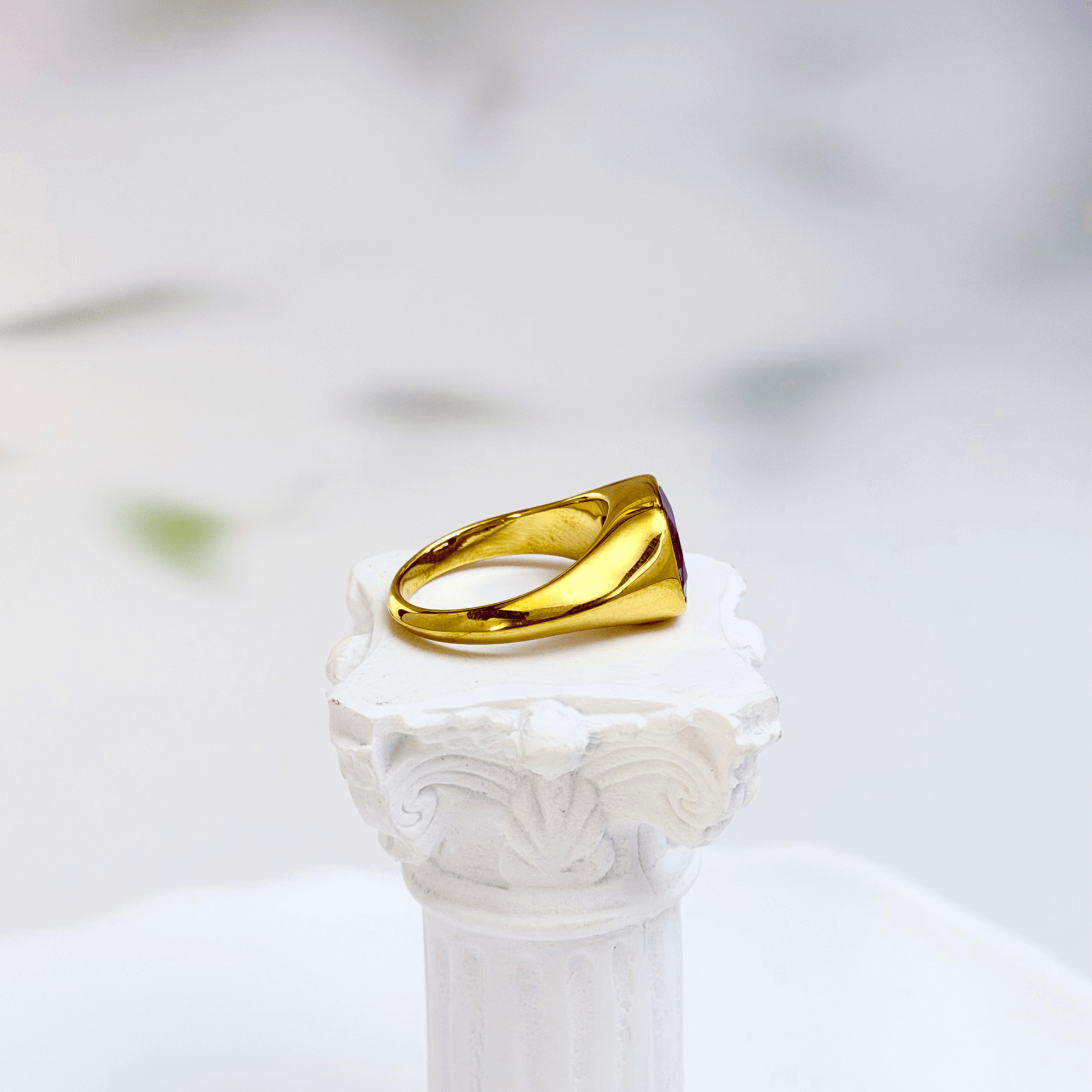 Gold ring with a cushion-cut amethyst-purple zircon gemstone.