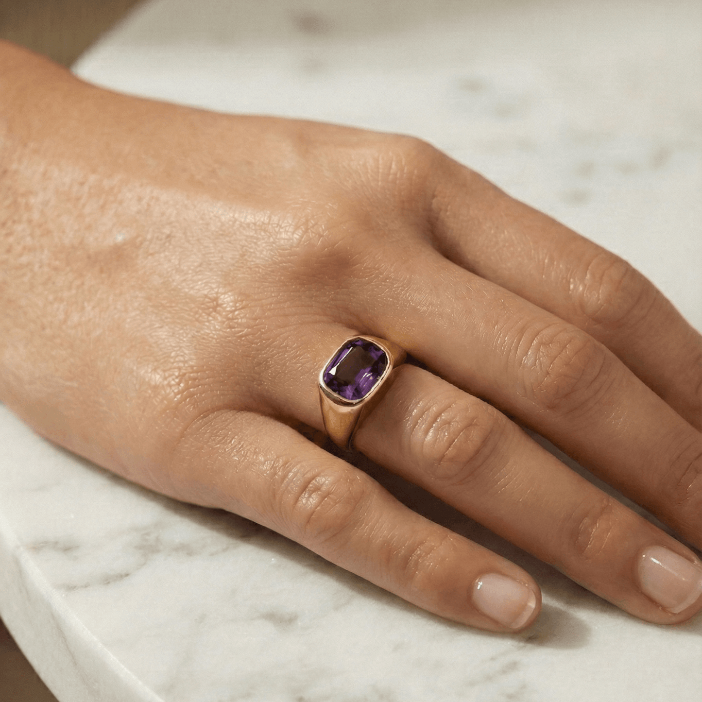 Gold ring with a cushion-cut amethyst-purple zircon gemstone.