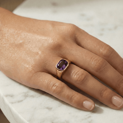 Gold ring with a cushion-cut amethyst-purple zircon gemstone.