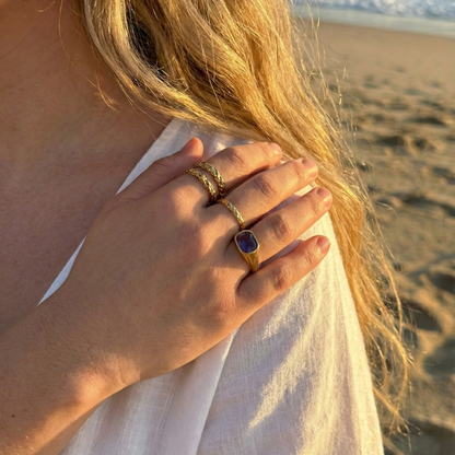 Gold ring with a cushion-cut amethyst-purple zircon gemstone.