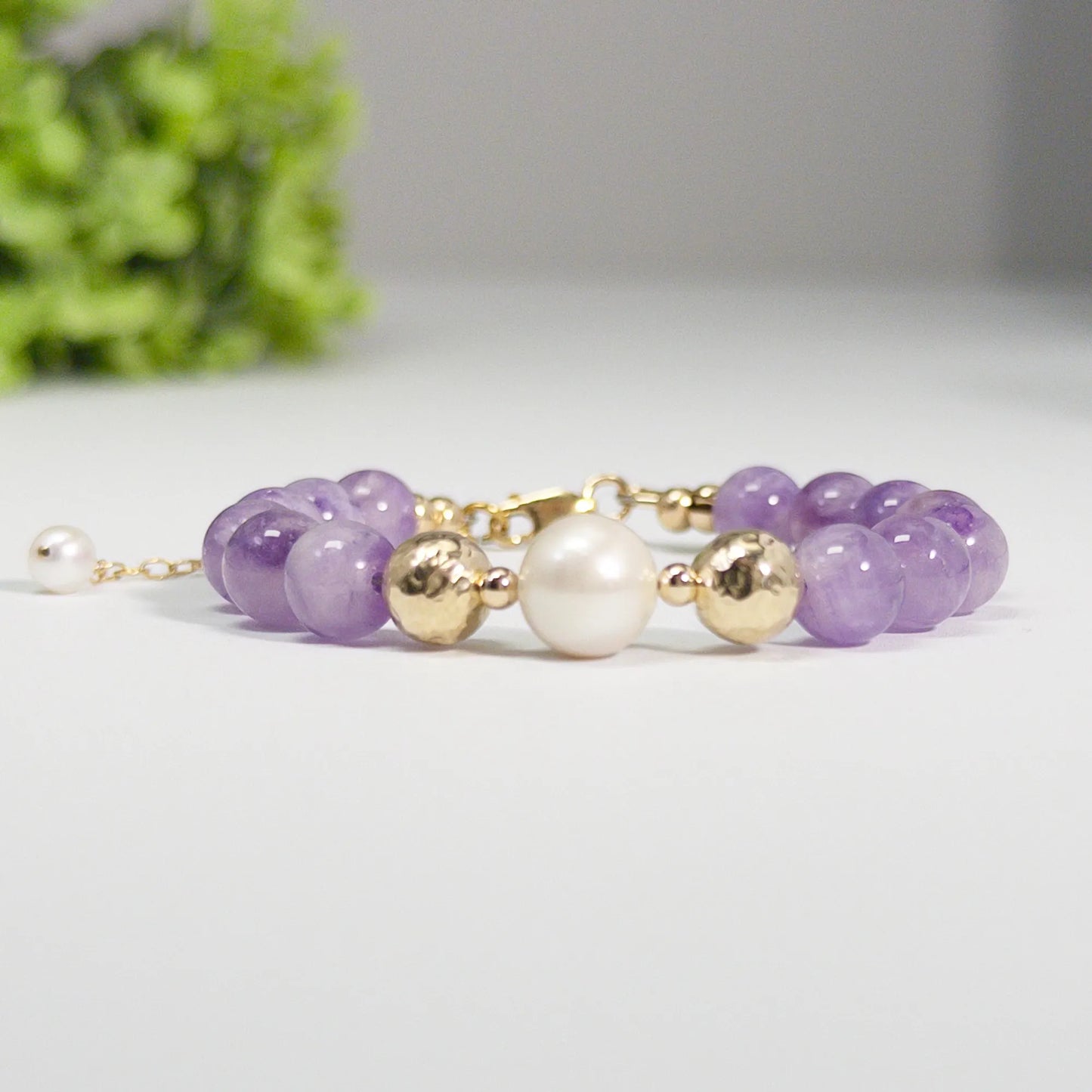 A beaded bracelet featuring Amethyst beads, premium freshwater pearl, and stamped initial disc, 14k gold filled. MXW Jewellery.