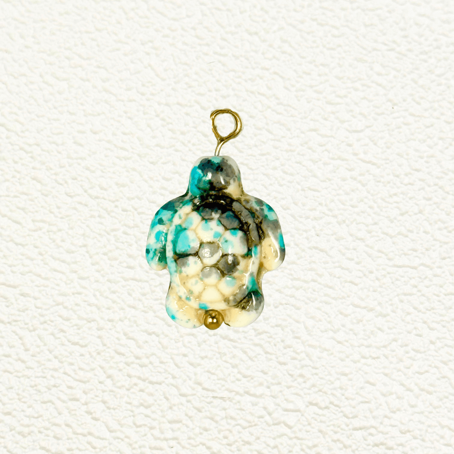 Turquoise-toned synthetic stone turtle charm with hexagonal mosaic shell pattern and gold bead detail