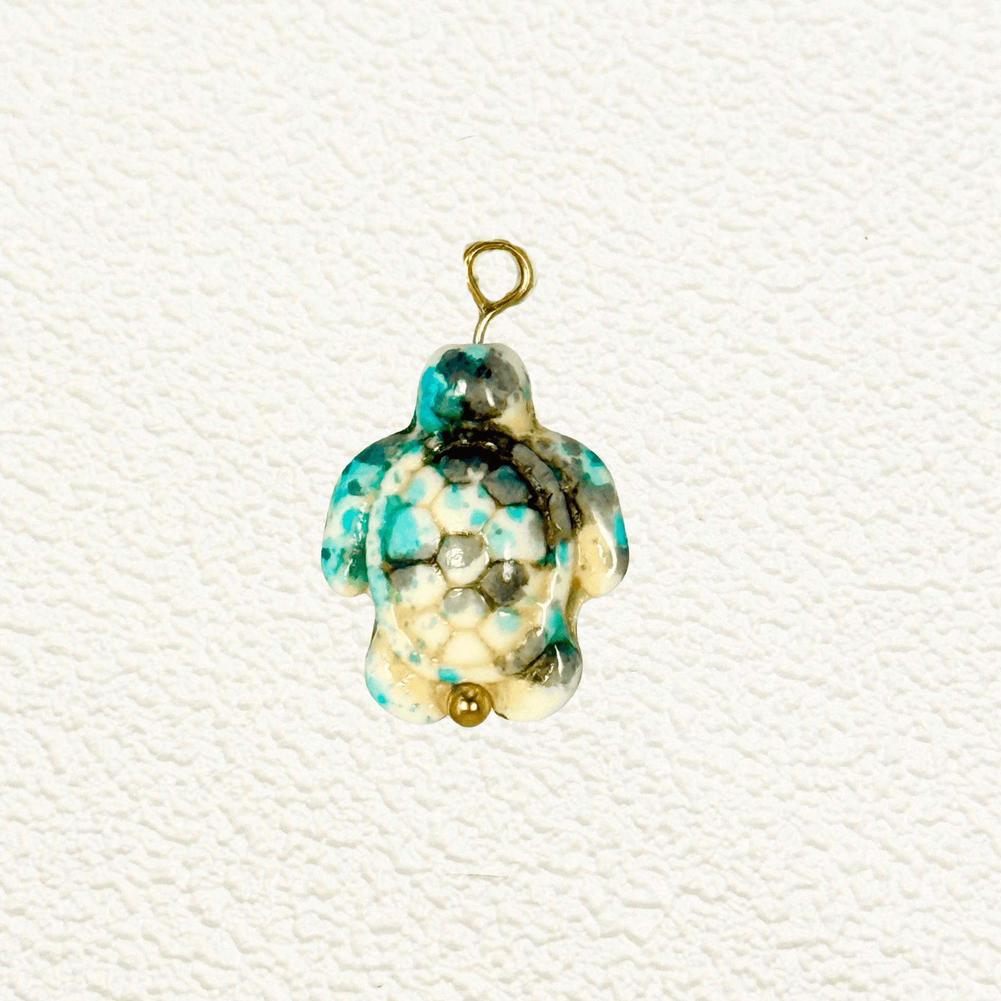 Turquoise-toned synthetic stone turtle charm with hexagonal mosaic shell pattern and gold bead detail