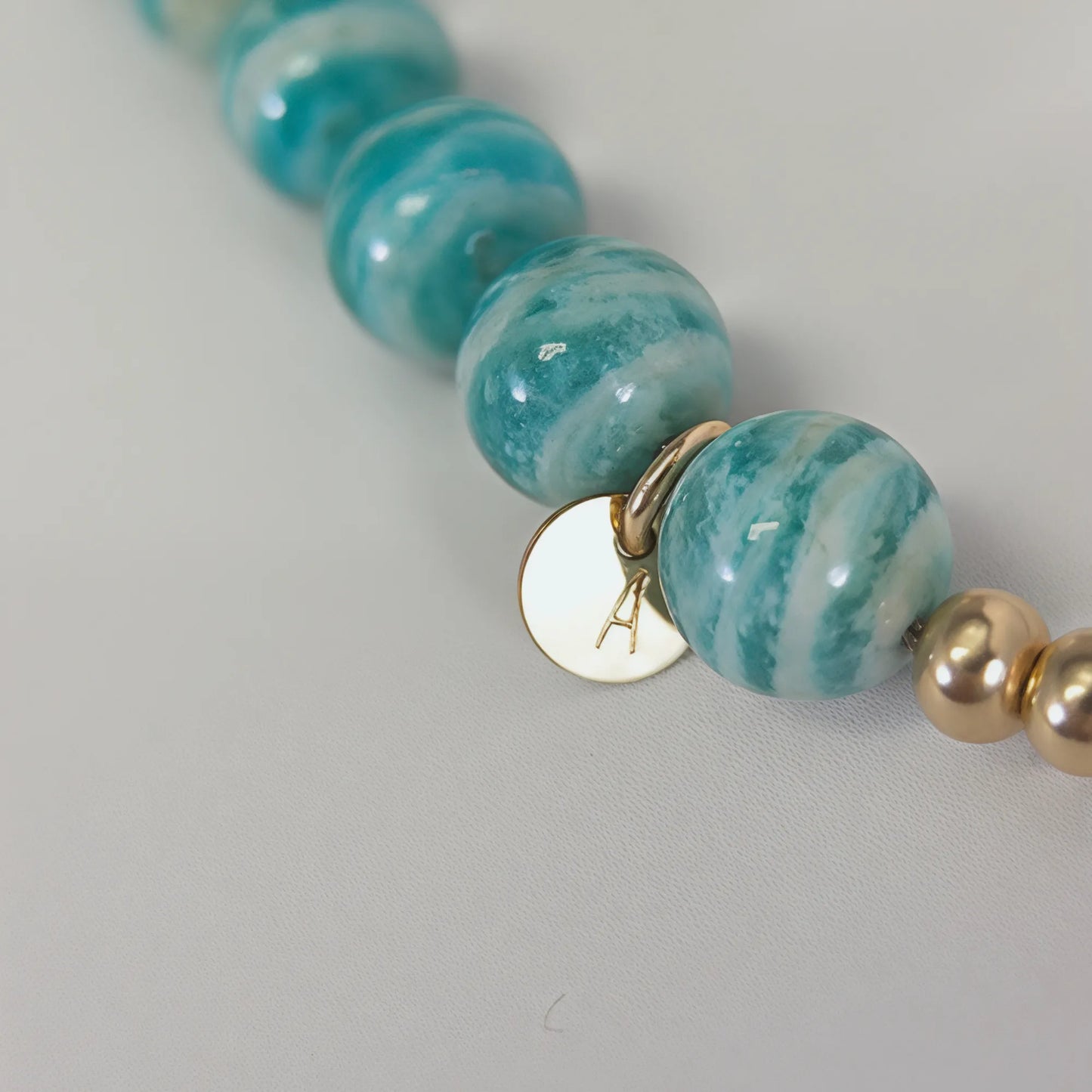 A beaded bracelet featuring banded amazonite gemstone beads, premium freshwater pearl, and personalised stamped initial disc, 14k gold filled. MXW Jewellery