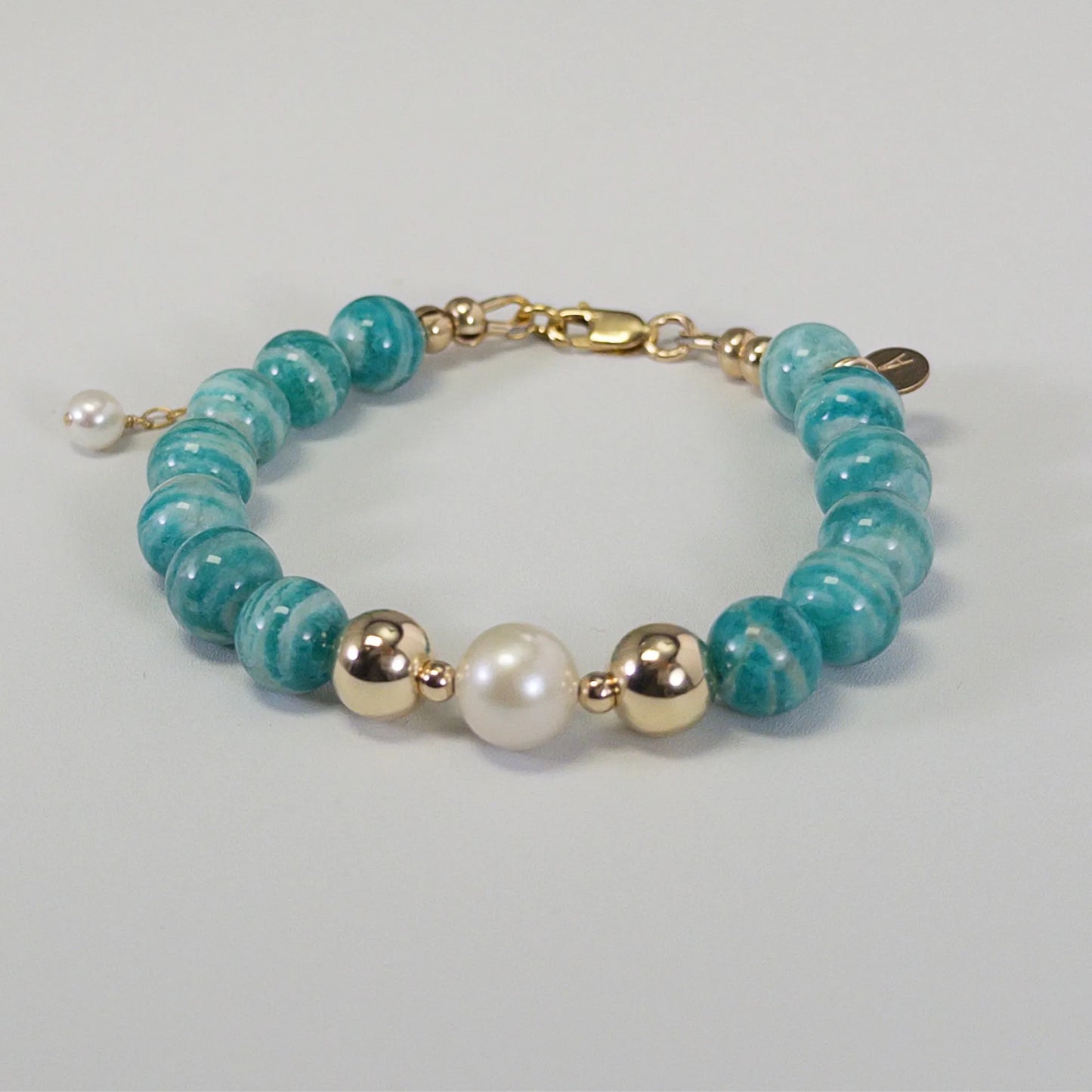 A beaded bracelet featuring banded amazonite gemstone beads, premium freshwater pearl, and personalised stamped initial disc, 14k gold filled. MXW Jewellery