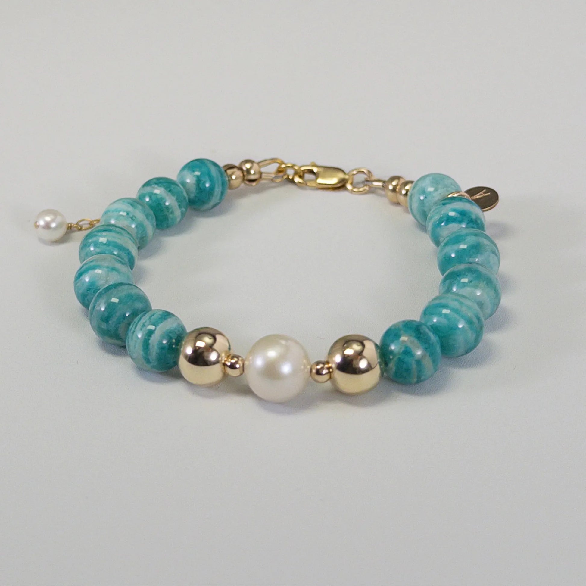 A beaded bracelet featuring banded amazonite gemstone beads, premium freshwater pearl, and personalised stamped initial disc, 14k gold filled. MXW Jewellery