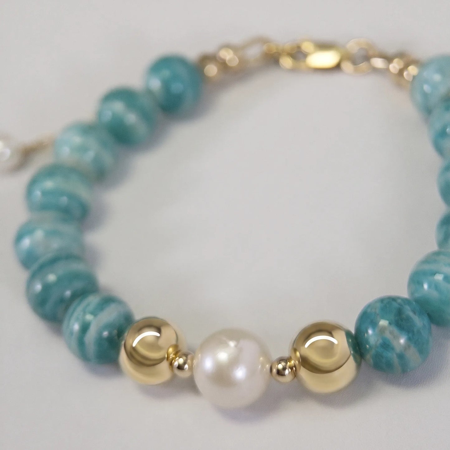 A beaded bracelet featuring banded amazonite gemstone beads, premium freshwater pearl, and personalised stamped initial disc, 14k gold filled. MXW Jewellery