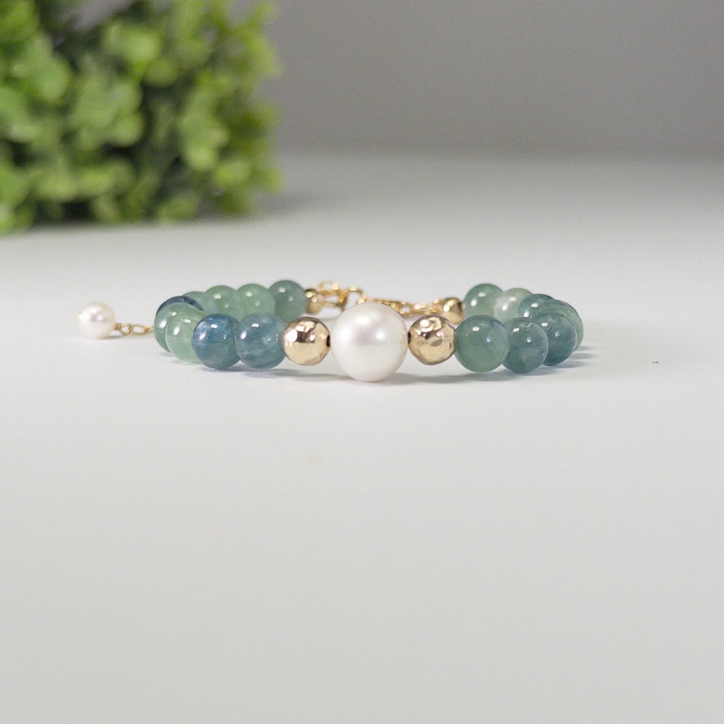 Bicolor kyanite, pearl and initial gold bracelet featuring naturally zoned blue-green gemstone beads, lustrous freshwater pearls and a personalised gold-filled stamped initial disc.
