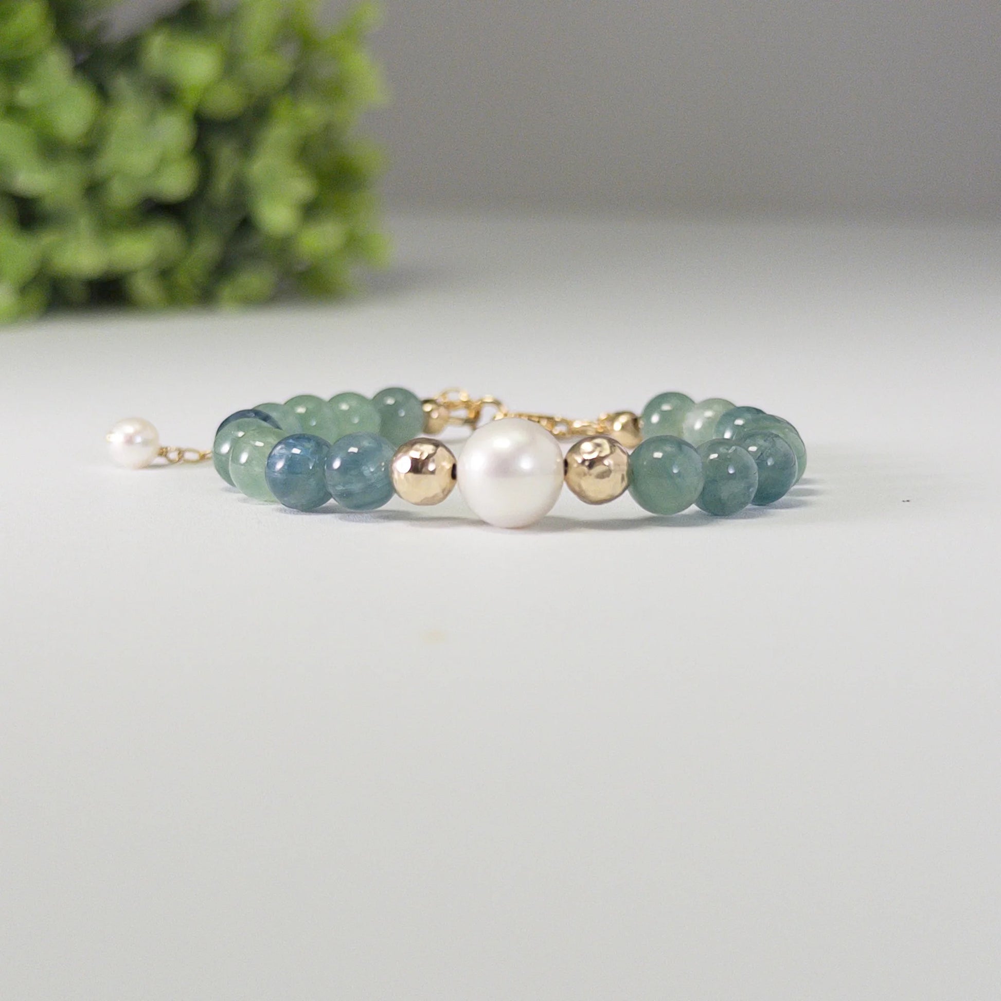 Bicolor kyanite, pearl and initial gold bracelet featuring naturally zoned blue-green gemstone beads, lustrous freshwater pearls and a personalised gold-filled stamped initial disc.