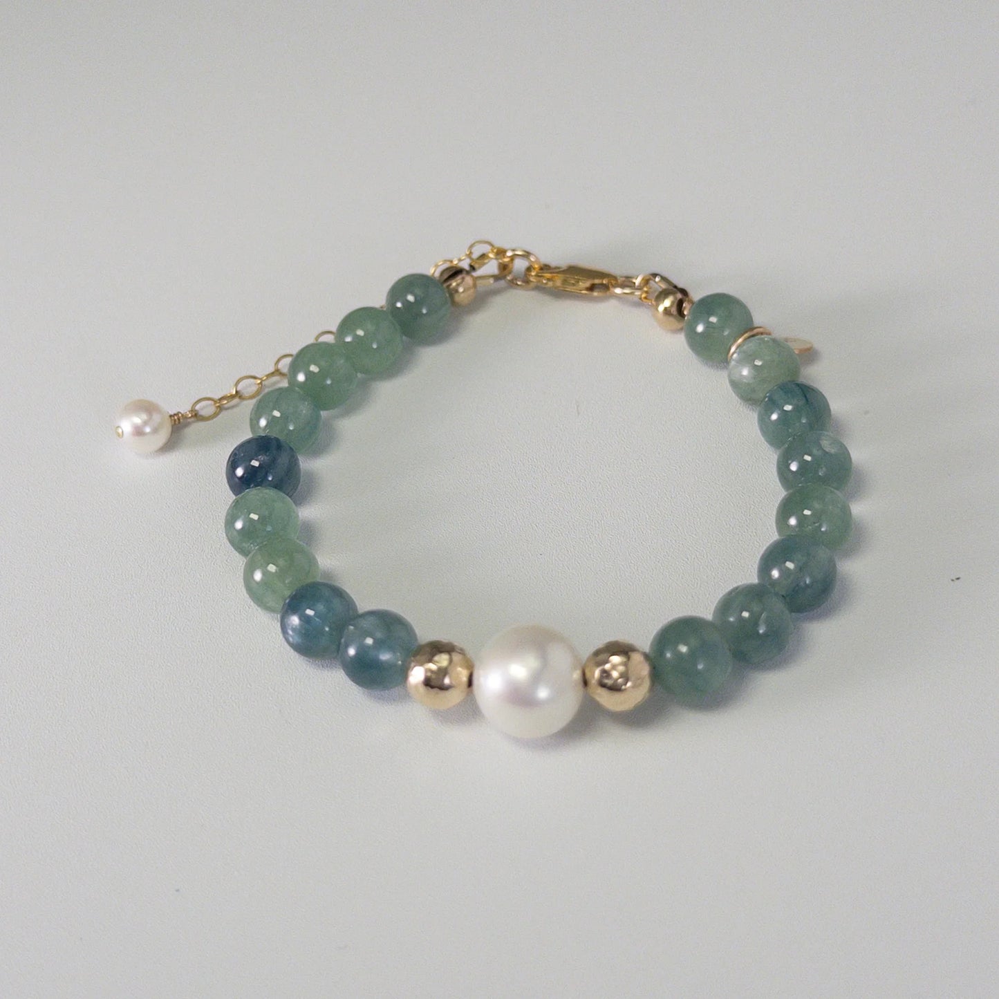 Bicolor kyanite, pearl and initial gold bracelet featuring naturally zoned blue-green gemstone beads, lustrous freshwater pearls and a personalised gold-filled stamped initial disc.