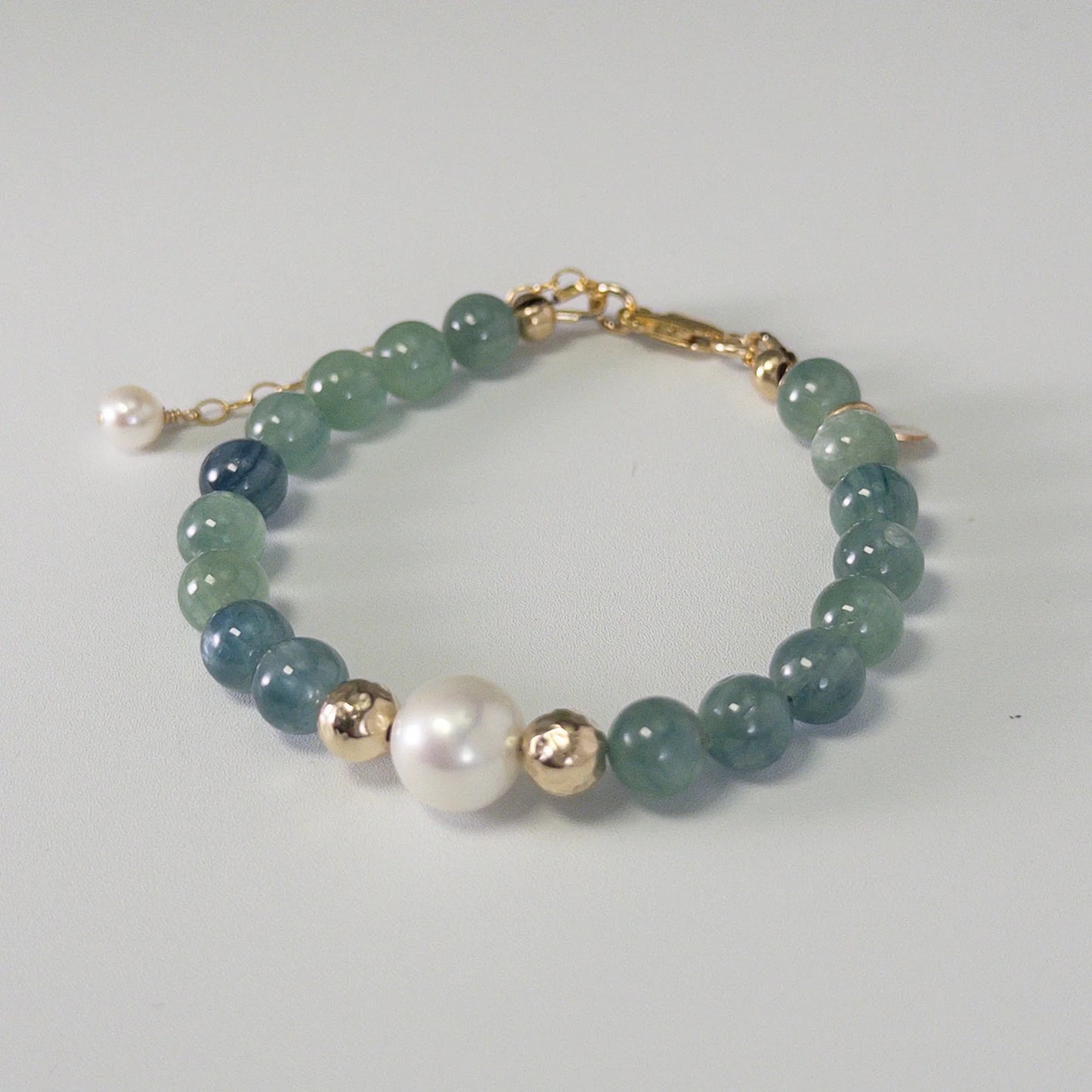 Bicolor kyanite, pearl and initial gold bracelet featuring naturally zoned blue-green gemstone beads, lustrous freshwater pearls and a personalised gold-filled stamped initial disc.
