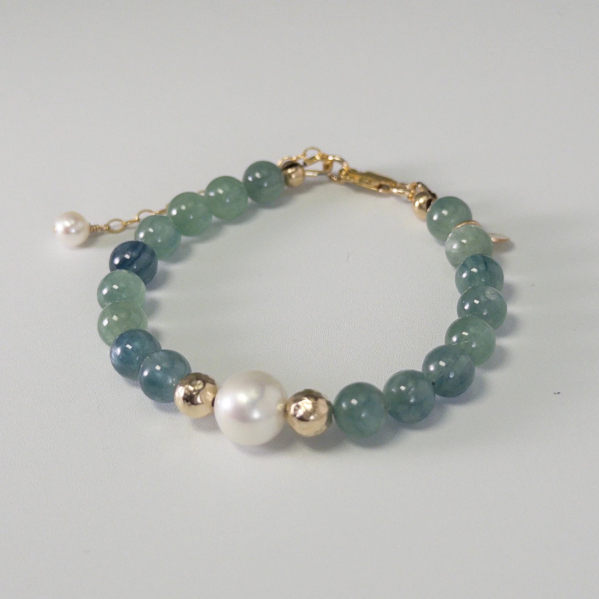 Bicolor kyanite, pearl and initial gold bracelet featuring naturally zoned blue-green gemstone beads, lustrous freshwater pearls and a personalised gold-filled stamped initial disc.