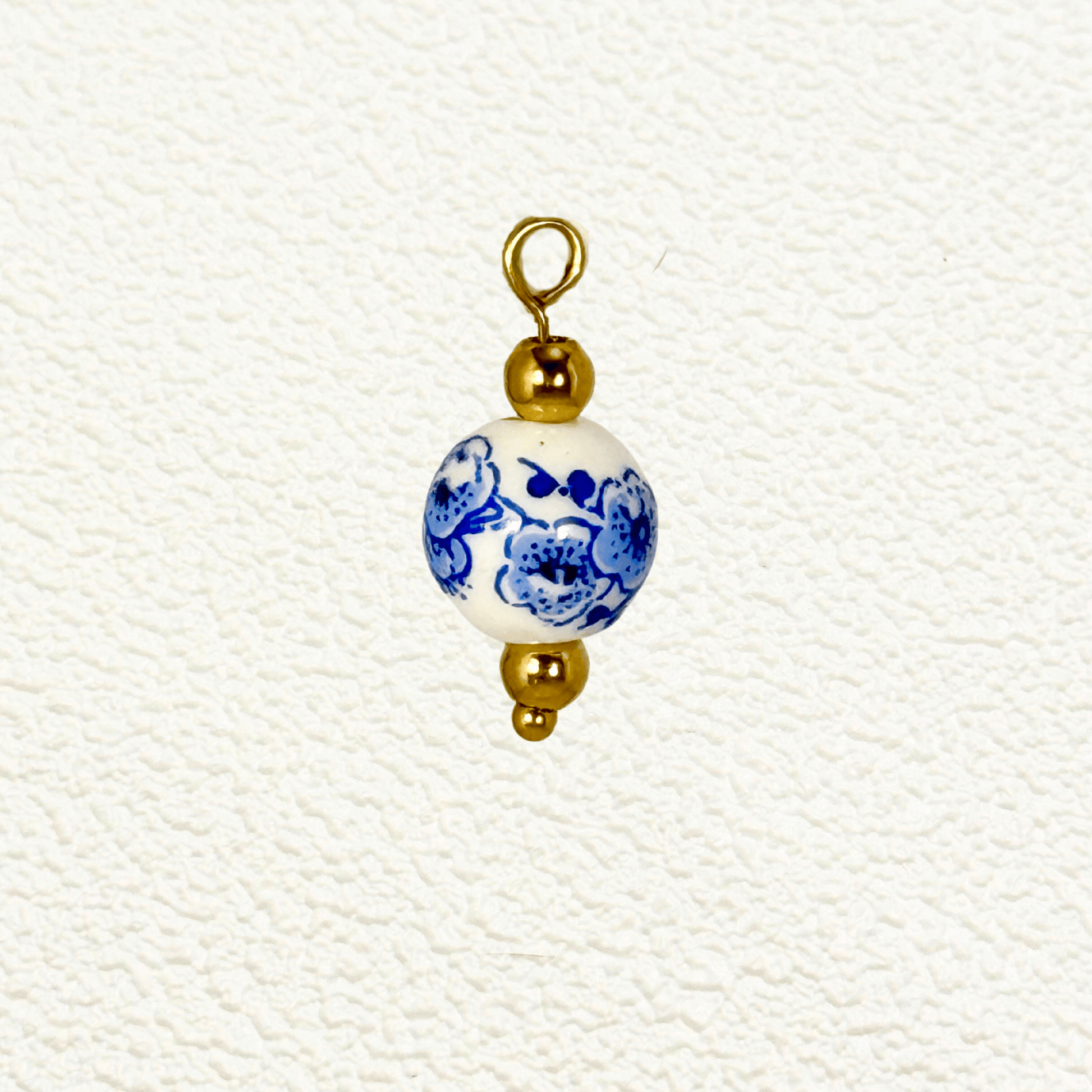 White ceramic charm with blue blossom floral design and gold beads