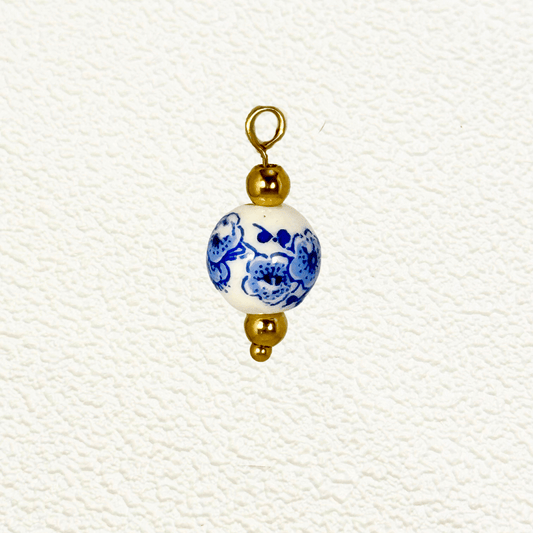 White ceramic charm with blue blossom floral design and gold beads