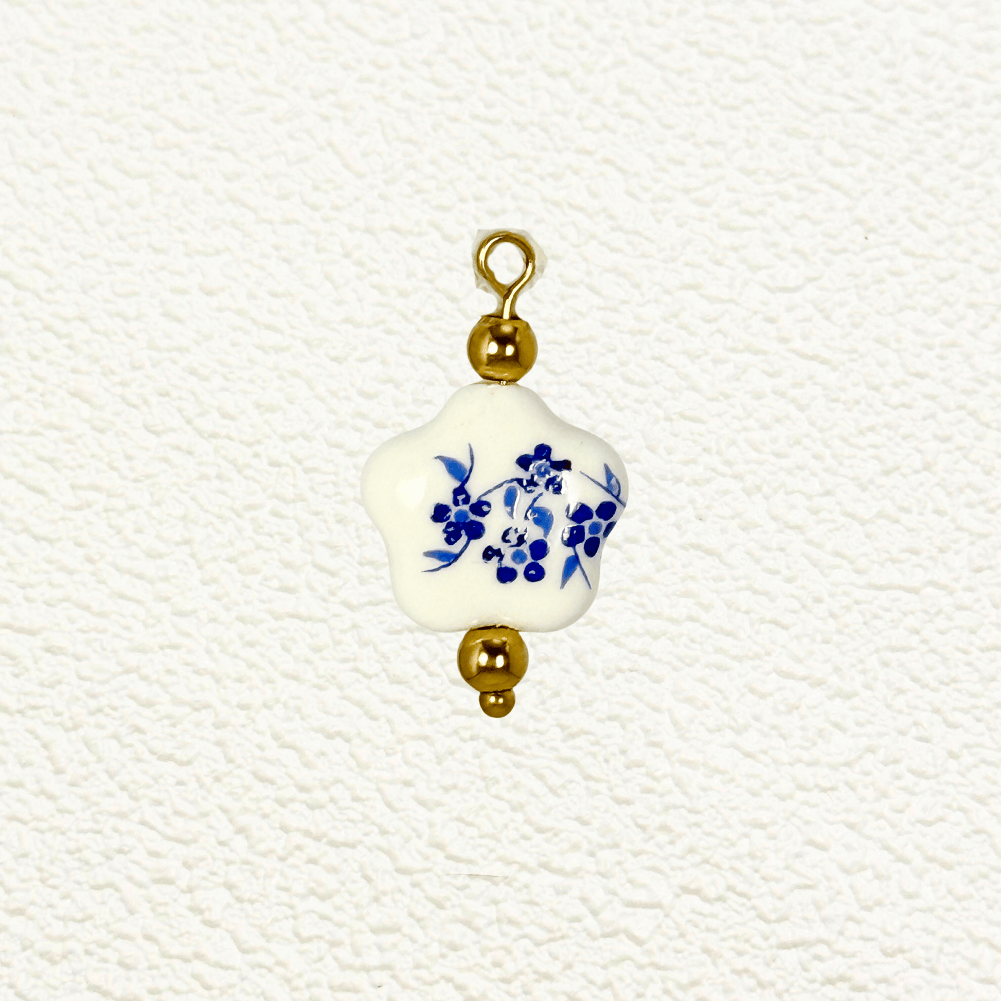 Star-shaped white ceramic charm with blue floral design and gold bead accents