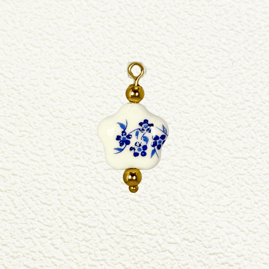 Star-shaped white ceramic charm with blue floral design and gold bead accents
