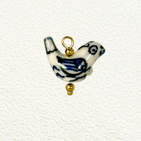 Hand-painted white ceramic charm in the shape of a bird with blue wing detailing and gold beads