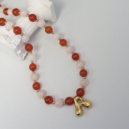 personalised 14K gold filled necklace with alternating carnelian and pink morganite beads, gold spacers and bubble initial letter.