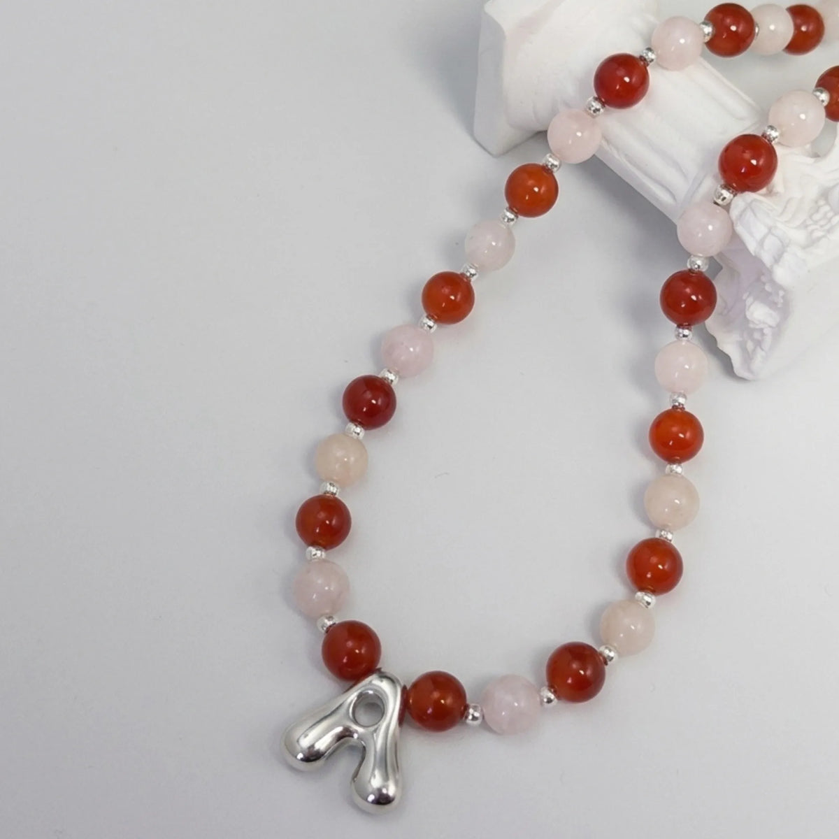 personalised necklace with alternating carnelian and pink morganite beads, silver spacers and bubble initial letter.