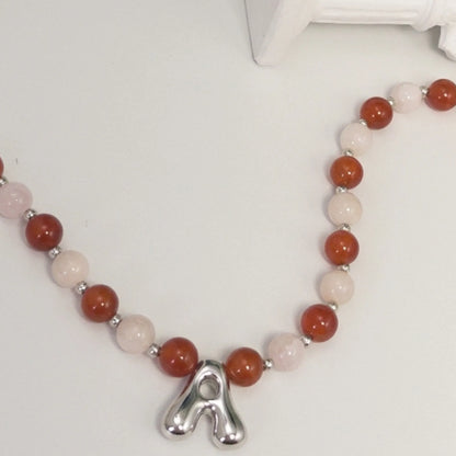 personalised necklace with alternating carnelian and pink morganite beads, silver spacers and bubble initial letter.