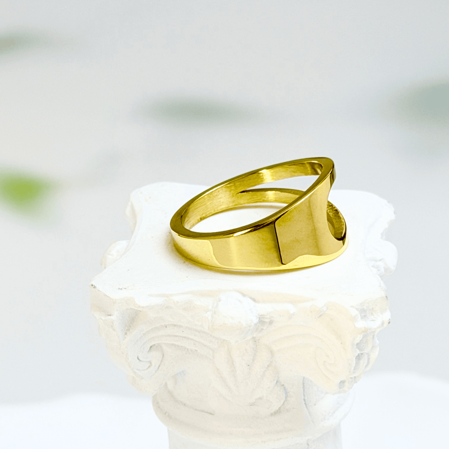 gold carved arc ring on white background, minimal sculptural gold ring